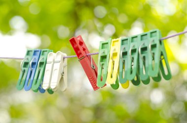 Yeşil bokeh arka plan üzerinde izole ip asılı plastik renk clothespin.