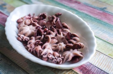 Ahşap bir arka planda, tabakta küçük ahtapotlar. Sağlıklı deniz ürünleri fotoğrafı..