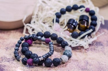 Doğal taşlardan yapılmış lav bilekliği. Gerekli yağlarla el yapımı mücevher şişesi. Aroma terapi fotoğrafı..