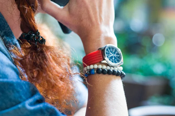 Female hand with a watch and a natural stoun bracelet holds a phone.