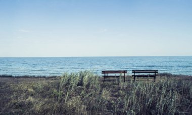 Deniz kenarında çimlerin üzerinde iki boş bank. Doğal manzara romantik fotoğrafı..
