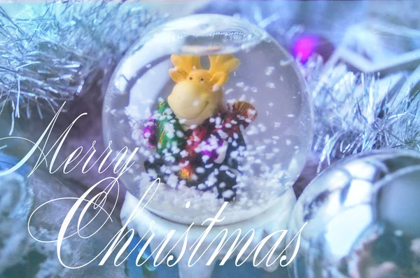 Feliz Navidad y Feliz Año Nuevo tarjeta festiva con bola de nieve y oropel de árbol de Navidad. Bola de cristal de nieve con juguete de alce . — Foto de Stock