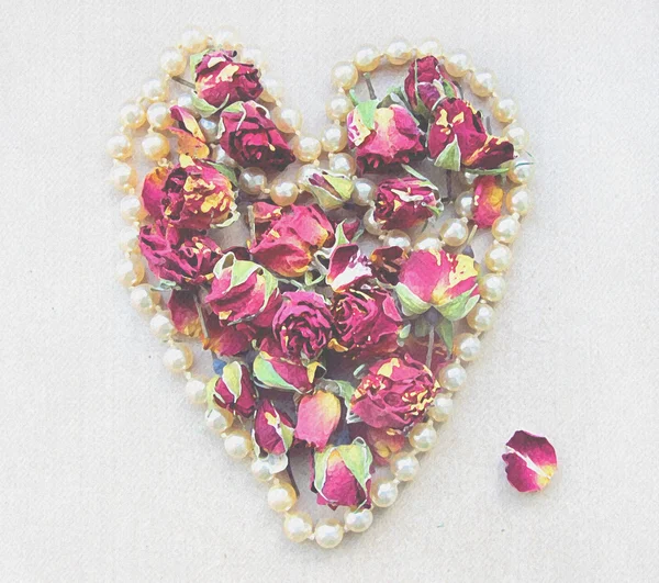 Gentle background with pink rosebud, petals and heart shaped pearl necklace isolated on white for wedding decoration.