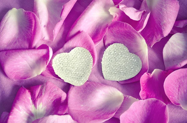 Background texture of beautiful pink rose petals and two hearts. The concept of love and romance. Valentines Day decor. — Stock Photo, Image