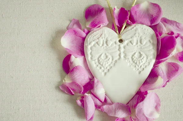 Vintage stijl decoratieve houten witte hart, met roze roos toppen en op textiel oppervlak, shabby chic en romantisch. — Stockfoto