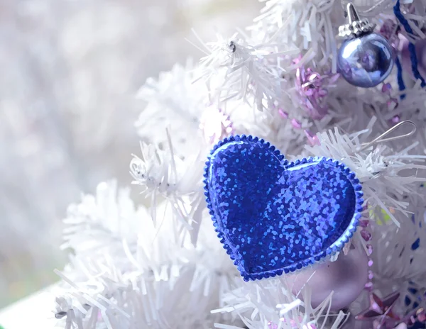 Blue heart hanging on artificial Christmas tree branch. Christmas decor. Winter holidays, celebration concept — Φωτογραφία Αρχείου