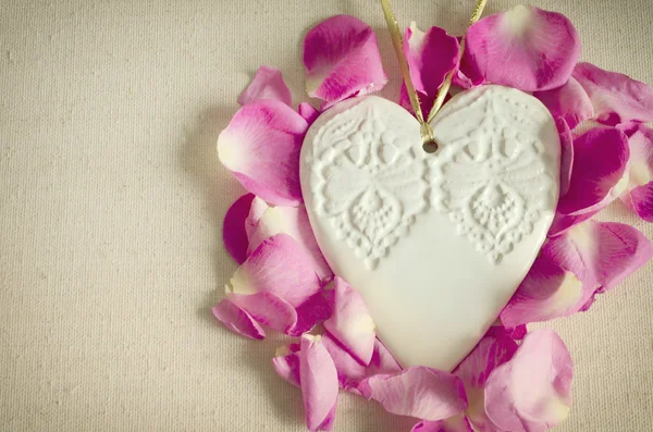 Vintage style ornamental wooden white heart, with pink rose buds and on textile surface, shabby chic and romantic. — Stock Photo, Image