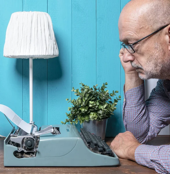 A middle age man write with an old typewriter