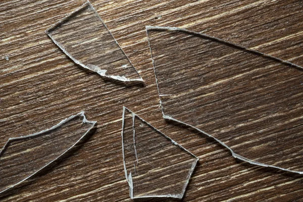 Eski ahşap bir masanın üzerinde kırık cam parçaları var.