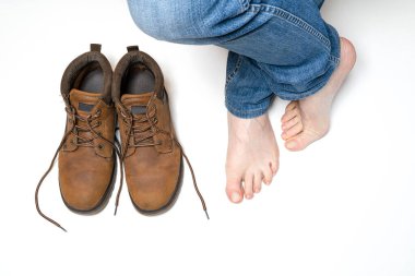 Bir çift ayakkabı ve çıplak ayaklı bir adam.