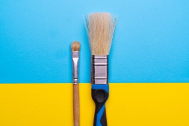 Renkli bir yüzeye yan yana yerleştirilmiş büyük ve küçük bir fırça.