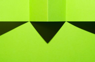 Katlanmış yeşil kağıt yüzeyde bir gölge oluşturur.