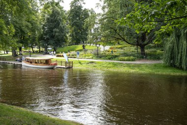 Riga, Letonya. 22 Ağustos 2021. Şehir merkezindeki parktan geçen nehirde turist taşımak için bir tekne.