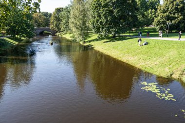Riga, Letonya. 22 Ağustos 2021. Şehir merkezindeki parktan geçen nehirde turist taşımak için bir tekne.