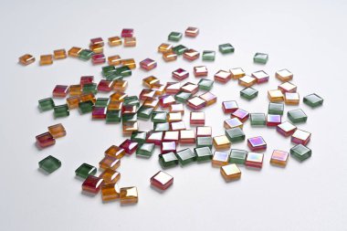 Beyaz bir yüzeye saçılmış renkli cam kiremitlerle yapılmış bir arka plan.