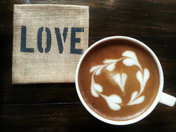 Café con leche sobre mesa de madera oscura con la palabra "AMOR" platillo — Foto de Stock