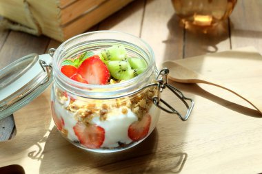 Healthy and colorful breakfast in warm morning: Low fat yoghurt with granola, strawberry and kiwi fruit clipart