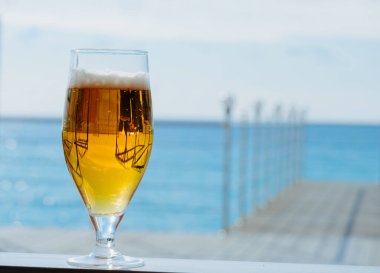 Güneşli bir günde, deniz restoranının terasında taze soğuk bir bardak bira. Fotokopi alanı bulanık.