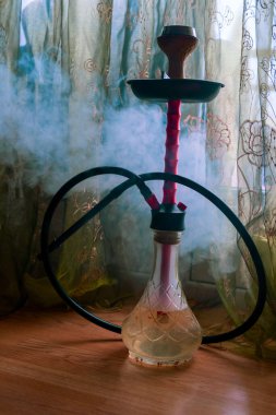 Bulanık tekstil arka planında duman olan seçici odaklı nargile. Doğulu nargile içme konsepti.