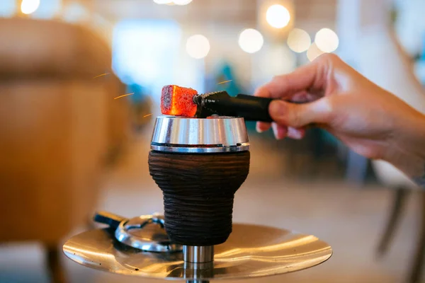 Close up metal hookah bowl with charcoal. Blurred background of the restaurant. Concept of hookah smoking. Selective focus.