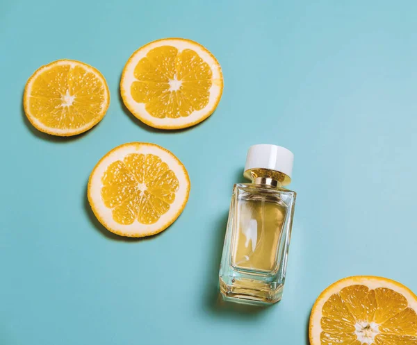 Beautiful composition with perfume and citrus slices on a blue pastel background, overhead view.