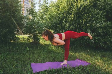 Kırmızı taytlı güzel bir kadın ve şehir parkında yoga yapan bir kadın.