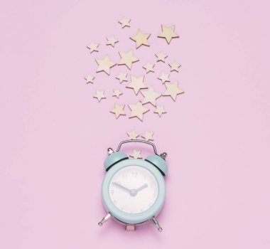Üstten mavi alarm saati ve pastel pembe arka planda yıldızlar. Kutlama minimal kartı.