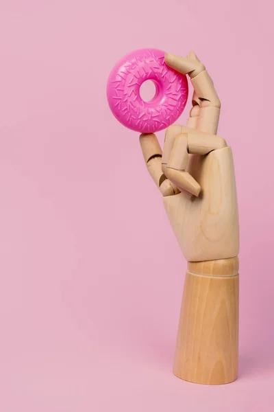 Holzhand Mit Rosa Donut Auf Pastellrosa Hintergrund Gefälschte Lebensmittel Aus — Stockfoto