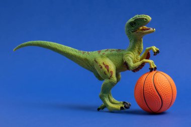 Basketbol toplu yeşil dinozor oyuncağı. Basketbol minimal kart mavi arkaplan.