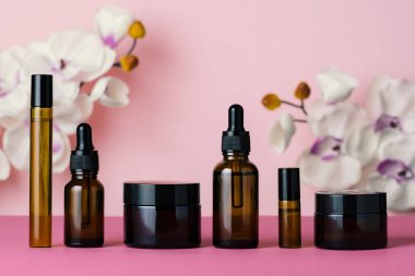 Kahverengi cam kozmetik şişeleri pembe arka planda. Güzellik konsepti.