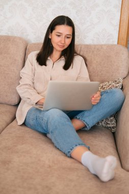 Evde dizüstü bilgisayar kullanan genç ve güzel bir kadın..