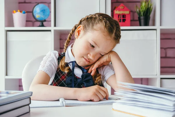 Yorgun, üzgün liseli kız ödevlerini yapıyor.