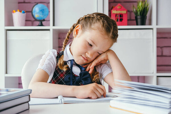 Уставшая грустная школьница сидит за уроками