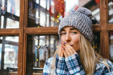 Genç ve güzel sarışın kız soğuk kış havasında ellerini ovuşturuyor..