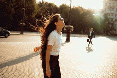 Genç ve mutlu esmer kadın yazın şehirde eğleniyor. Gerçek kadın şehir portresi..