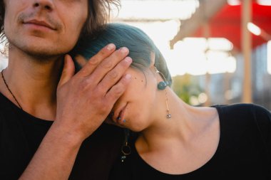 Genç bir adam genç bir kızın yüzünde elini tutuyor. Erkeğin eli kızın gözlerini kapatır. Cinsiyet ilişkileri, genç çiftlerin psikolojisi.