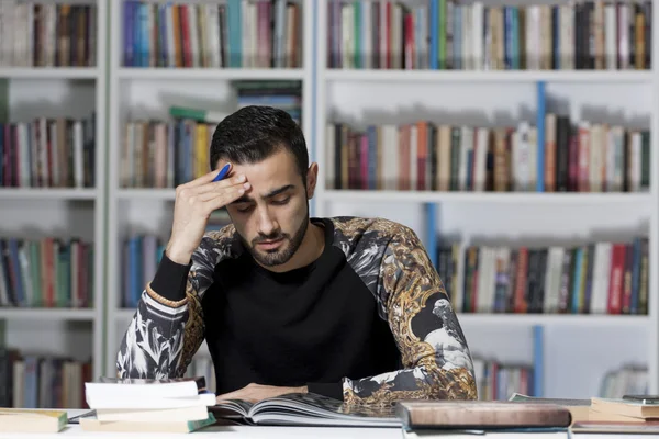 Retrato de belo jovem estudante na biblioteca — Fotografia de Stock