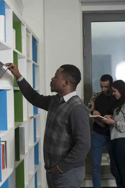 Studenten op zoek naar boeken in de bibliotheek — Stockfoto