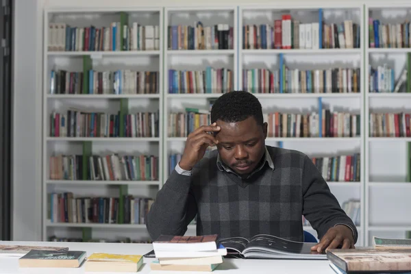 Portret van knappe jonge student in de bibliotheek — Stockfoto