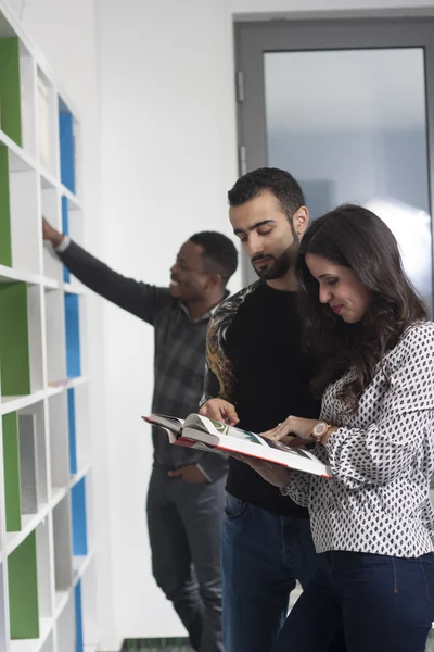 Studenten op zoek naar boeken in de bibliotheek — Stockfoto