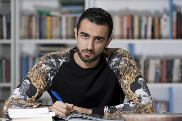 Retrato de belo jovem estudante na biblioteca — Fotografia de Stock