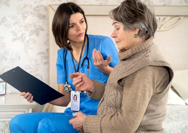 Young nurse is caring for an elderly 80-year-old woman at home — Stock Photo, Image