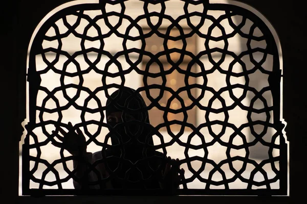 Muzułmanka w czarnym hidżabie stoi za wzorzystym, kutym żelaznym ogrodzeniem.. — Zdjęcie stockowe