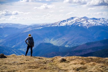 Gezgin, gün batımında karla kaplı dağların çarpıcı manzarasına bakıyor..