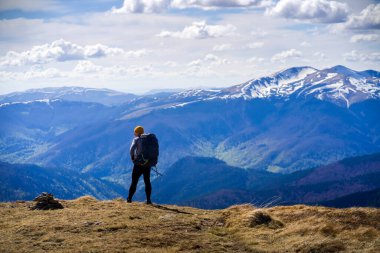 Gezgin, gün batımında karla kaplı dağların çarpıcı manzarasına bakıyor..