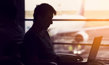 Adam havaalanında dizüstü bilgisayarla çalışıyor..