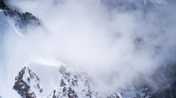Rotsen van de hooglanden, de weg tussen de besneeuwde toppen. — Stockfoto