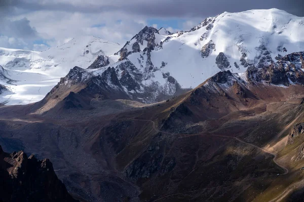 Rochers des hauts plateaux, la route parmi les sommets enneigés. — Photo