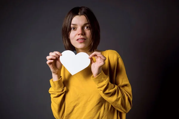 Молодая девушка держит белое бумажное сердце - открытку, чтобы написать о любви. — стоковое фото