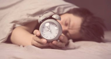 Battaniyenin altından genç bir adamın elleri çalar saati gri tutuyordu.. 